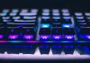 Easy Ways to Get Free Rust Skins A detailed close-up of illuminated mechanical keyboard keys with focus on blue and purple lights.