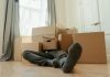 What to Do If You Fall at Work A person lies down tired among cardboard boxes in a bright room, depicting moving day stress.