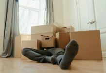 What to Do If You Fall at Work A person lies down tired among cardboard boxes in a bright room, depicting moving day stress.