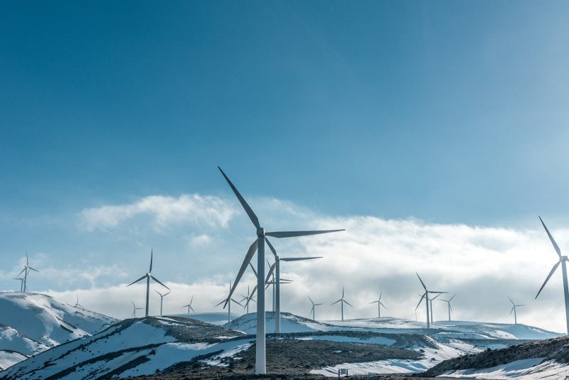 Photo by Jason Mavrommatis wind turbines on snowy mountain under clear blue sky during daytime
