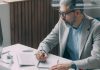 The Value of Fractional CFOs: Expertise, Flexibility, and Cost Savings A man sitting at a desk writing on a piece of paper