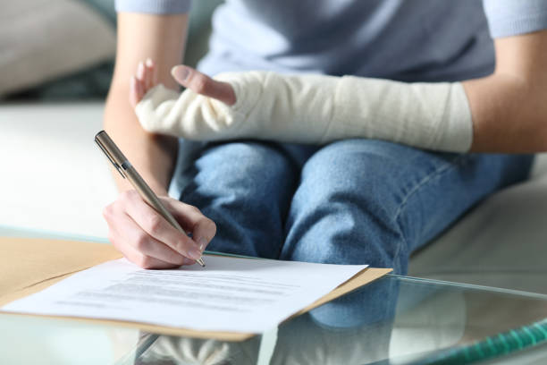 Disabled woman with bandaged arm signing document Disabled woman with bandaged arm signing document