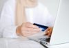 The Many Advantages of Online Payment Processing Close-up of a person holding a credit card while using a laptop for online shopping.