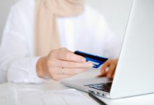 The Many Advantages of Online Payment Processing Close-up of a person holding a credit card while using a laptop for online shopping.