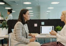 Why Communication Is the Most Underrated Power Skill Two women talking at a desk in an office.