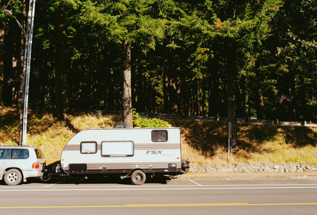 Photo by Adrian Newell a truck towing a camper on the side of the road