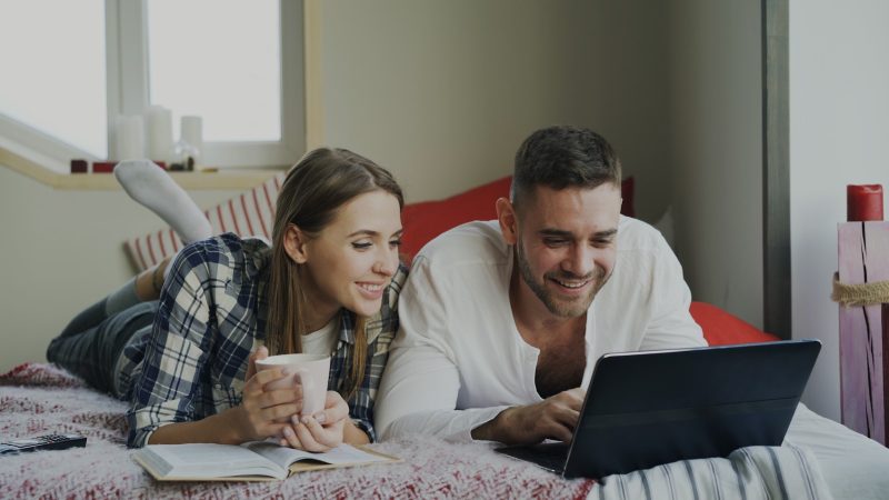 Photo by Vitaly Gariev Couple looking at a laptop on a bed