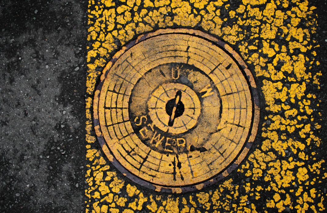 Yellow and black pavement surrounds a sewer cover.