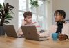 man and woman sitting at table using macbook