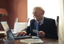 Fortifying Your Fortress: Unconventional Strategies for Enhanced Asset Protection Senior man in formal attire using a laptop and holding money, symbolizing financial success.