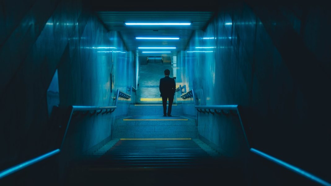 A man is walking down a dark hallway