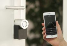 Why Smart Door Sensors Are the One Home Security Upgrade Every Apartment Renter Should Consider in 2026 gold Apple iPhone smartphone held at the door