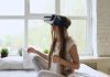 Young woman using virtual reality headset on bed
