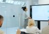 Woman presents charts on a screen to colleagues.