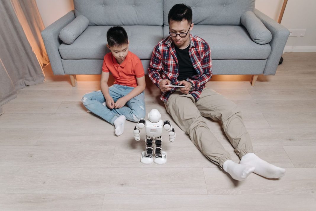 Photo by Pavel Danilyuk Father and son bonding over robotics and technology at home, enjoying playful interaction with a robot.