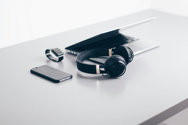 Photo by Christopher Gower black cordless headphones beside closed black laptop computer and smartphone