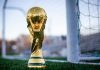 a golden soccer trophy sitting on top of a field
