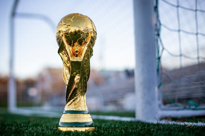Photo by My Profit Tutor a golden soccer trophy sitting on top of a field