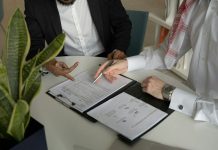 Tips for Writing Enforceable Business Contracts two men sitting at a table with papers and a pen