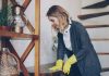 Woman wearing yellow gloves cleaning wooden surface