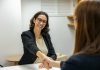 The Right Way to Hire a woman shaking hands with another woman sitting at a table