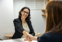 The Right Way to Hire a woman shaking hands with another woman sitting at a table
