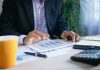 How to Use an SWP Calculator: Plan Monthly Withdrawals Without Depleting Your Corpus person in black suit jacket holding white tablet computer