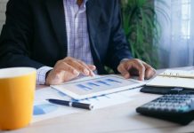 How to Use an SWP Calculator: Plan Monthly Withdrawals Without Depleting Your Corpus person in black suit jacket holding white tablet computer