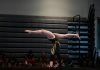 Grip, Protect, Perform: Essential Gymnastic Protection and Accessories for Peak Performance Gymnast performs a handstand on the balance beam.