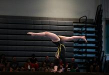 Grip, Protect, Perform: Essential Gymnastic Protection and Accessories for Peak Performance Gymnast performs a handstand on the balance beam.