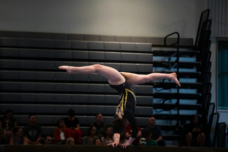 Photo by Naveen Ketterer Gymnast performs a handstand on the balance beam.