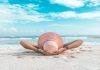 How to Plan a Restorative Vacation That Actually Combats Burnout woman in brown sun hat lying on sand during daytime