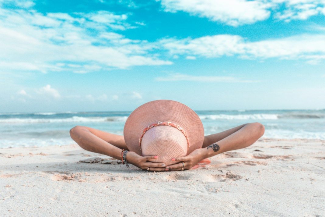 Photo by Rafael Cisneros Méndez woman in brown sun hat lying on sand during daytime