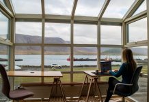 Why Top Executives Are Trading Boardrooms for Remote Luxury Workations person in blue jacket sitting on brown wooden chair near brown wooden table during daytime